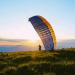 silhouette of person riding parachute during sunset