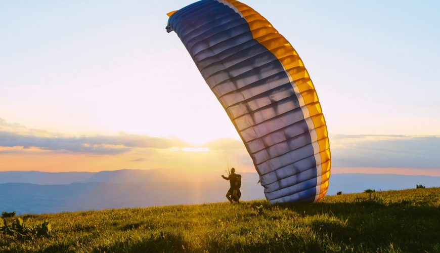 silhouette of person riding parachute during sunset